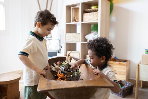 Two boys are playing with a wooden bowl in a playroom.